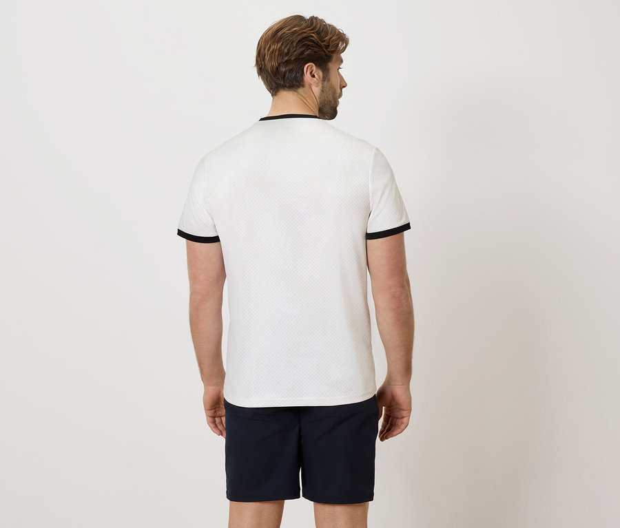 Rückansicht eines Mannes mit Bart, der ein weißes Poloshirt mit schwarzen Bündchen und marineblaue Shorts trägt.