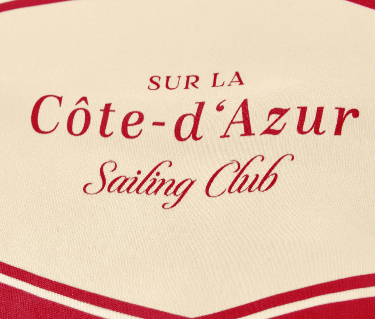 Nahaufnahme des Street One Halstuchs »Nicki« mit rotem Schriftzug "Côte-d'Azur Sailing Club" auf beigem Grund.