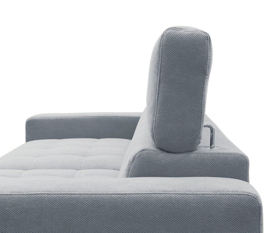 Nahaufnahme eines hellgrauen Stoffsofas mit gesteppter Sitzfläche und verstellbarer Kopfstütze. Die Kopfstütze wird von einer silbernen Metallstange gehalten. Eine Armlehne ist links sichtbar. Der Hintergrund ist weiß.