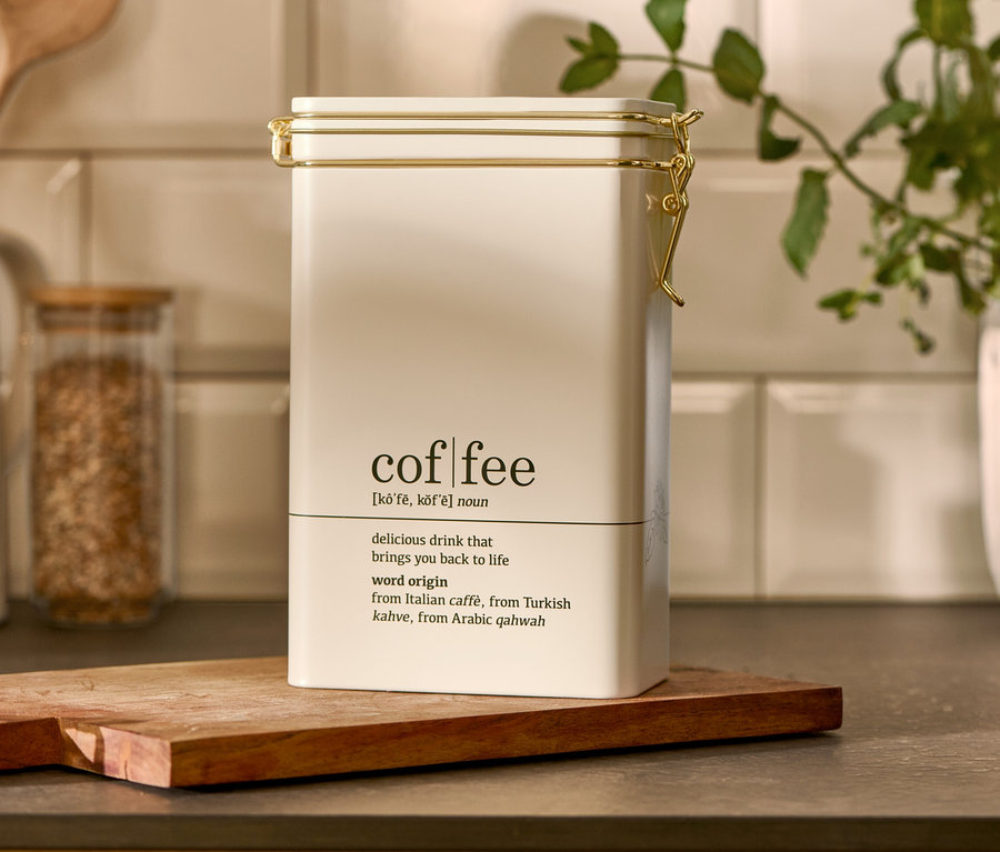 Eine weiße Kaffeedose, Coffee Dictionary steht auf einem Holzbrett.