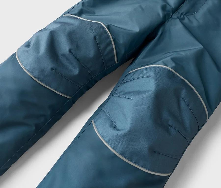 Nahaufnahme einer dunkelblauen Hose mit verstärkten Kniepartien, die von hellen reflektierenden Streifen umrandet sind.