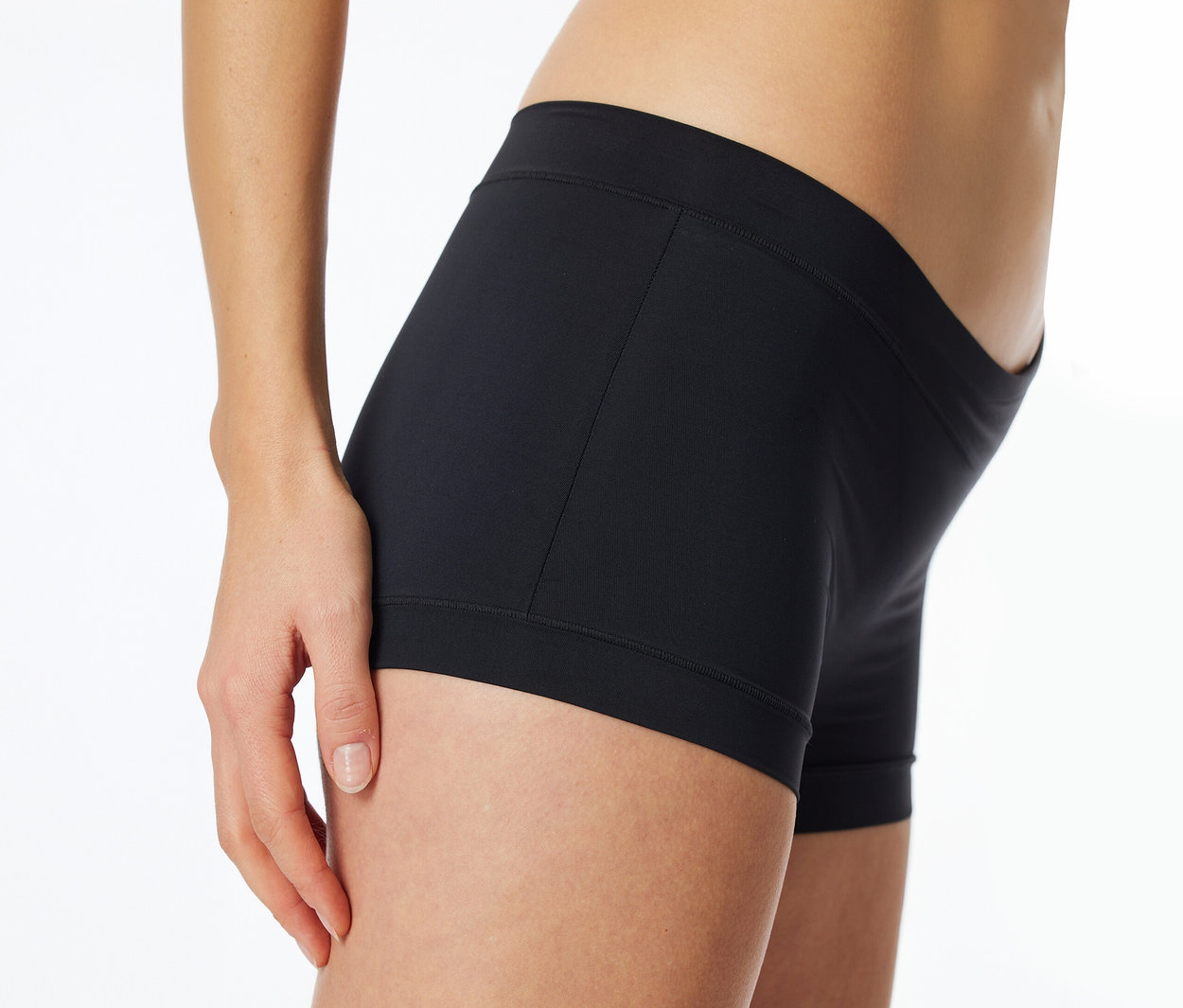 Seitenansicht einer Person, die schwarze, eng anliegende Boxershorts trägt, mit einer Hand, die auf dem Oberschenkel ruht.