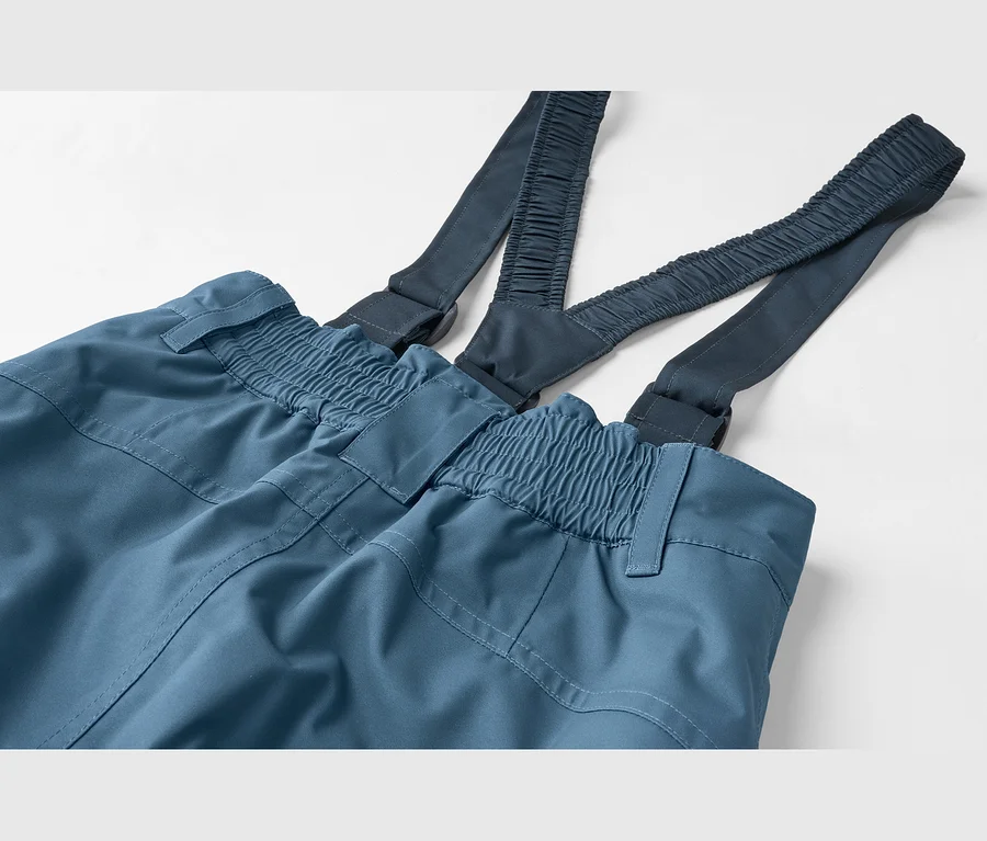 Nahaufnahme einer blauen Hose mit dunkelblauen Hosenträgern. Die Hose hat einen elastischen Bund, die Hosenträger sind gerafft.