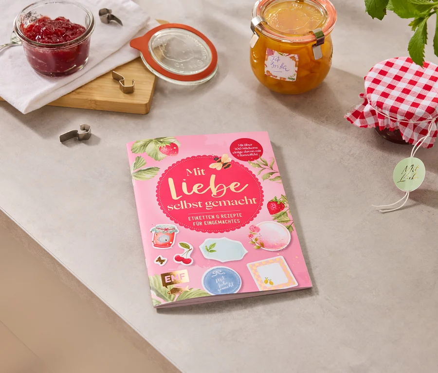 Auf einer Arbeitsfläche liegen Marmeladengläser und das Buch »Mit Liebe selbstgemacht«.