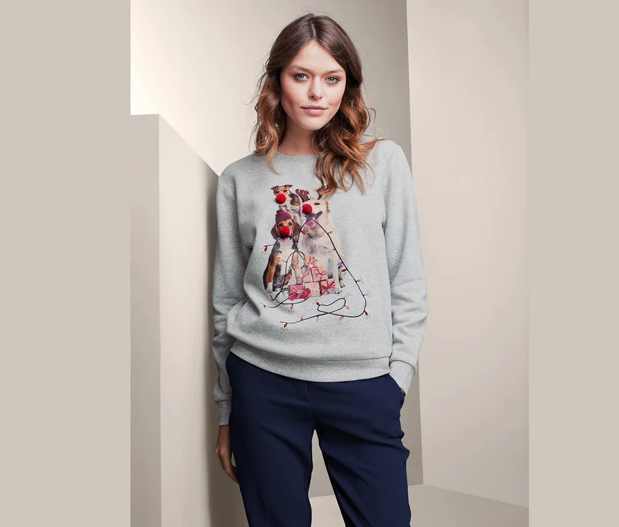 Frau trägt ein graues Sweatshirt mit einem weihnachtlichen Hunde-Motiv.