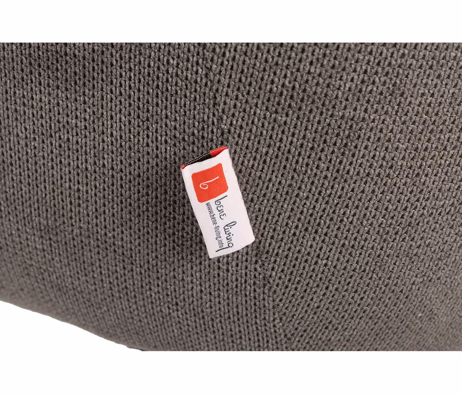 Nahaufnahme eines dunkelgrauen, gestrickten Stoffs des deVries Diningsessels Ginosa mit einem weißen Etikett, das „loene living“ und „www.loene-living.info“ zeigt.