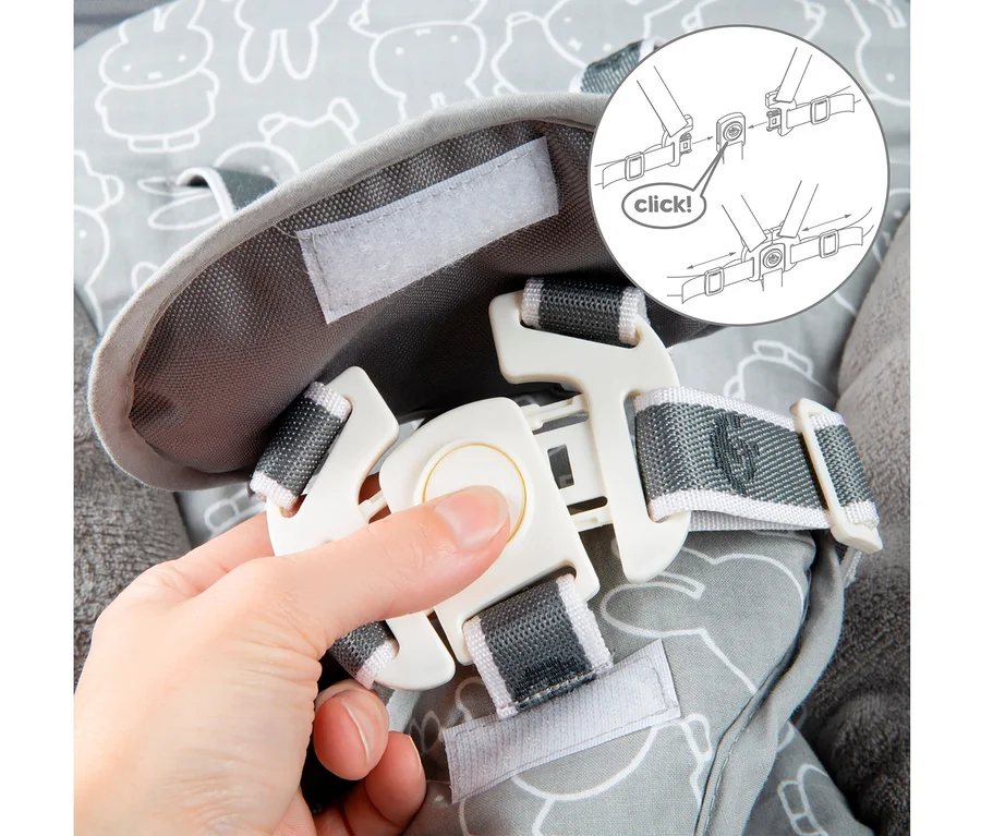 Eine Hand schließt einen weißen Plastiksicherheitsgurt über einem grauen Stoff mit einem Cartoon-Design.