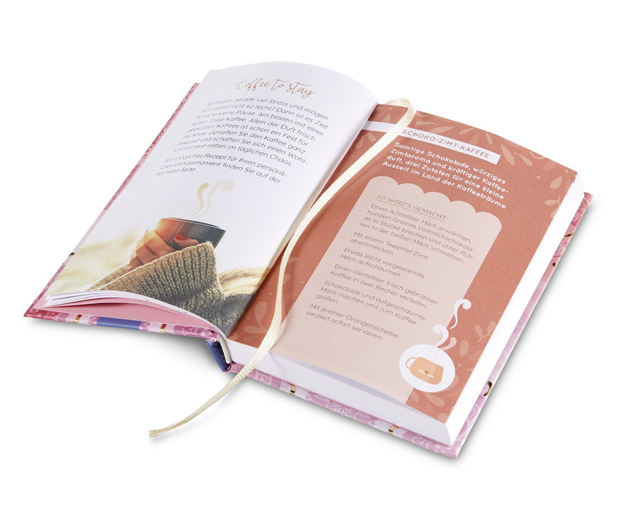 Offenes Buch „Das Glück wohnt überall“ mit Abbildung einer Kaffeetasse.
