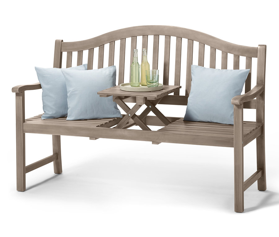 Eine graue 3-Sitzer-Gartenbank mit hochklappbarem Tabletttisch, auf dem sich zwei Flaschen und ein Glas befinden, ergänzt durch zwei hellblaue Kissen.