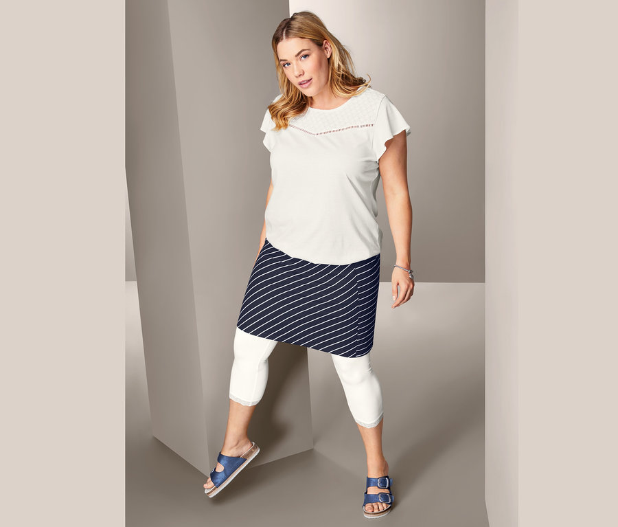 Frau posiert in Shirt mit Lochstickerei, gestreiftem Jerseyrock und 3/4-Leggings mit Spitzenborte.