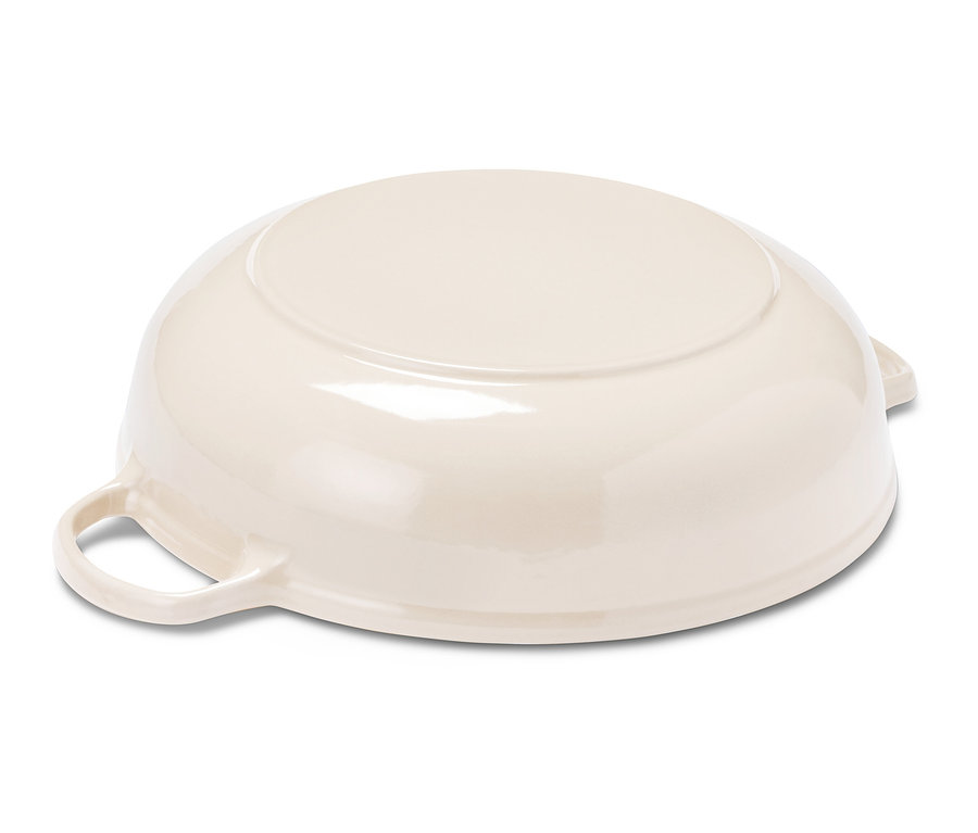 Eine cremefarbene Bräter-Pfanne liegt auf der Seite.