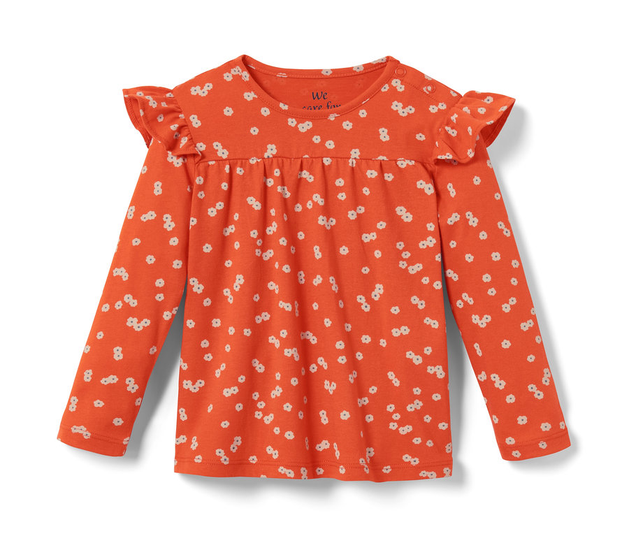 Orangefarbenes Baby-Langarmshirt mit weißen Blumenmuster und Rüschen an den Schultern.