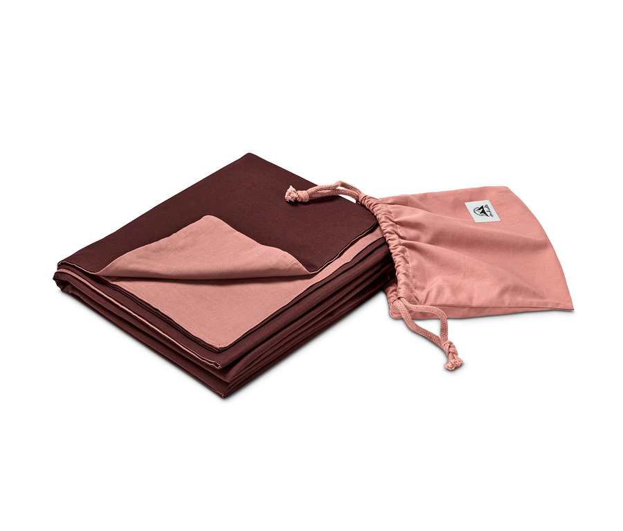 Ein Hüttenschlafsack liegt gefaltet neben einem rosa Beutel.