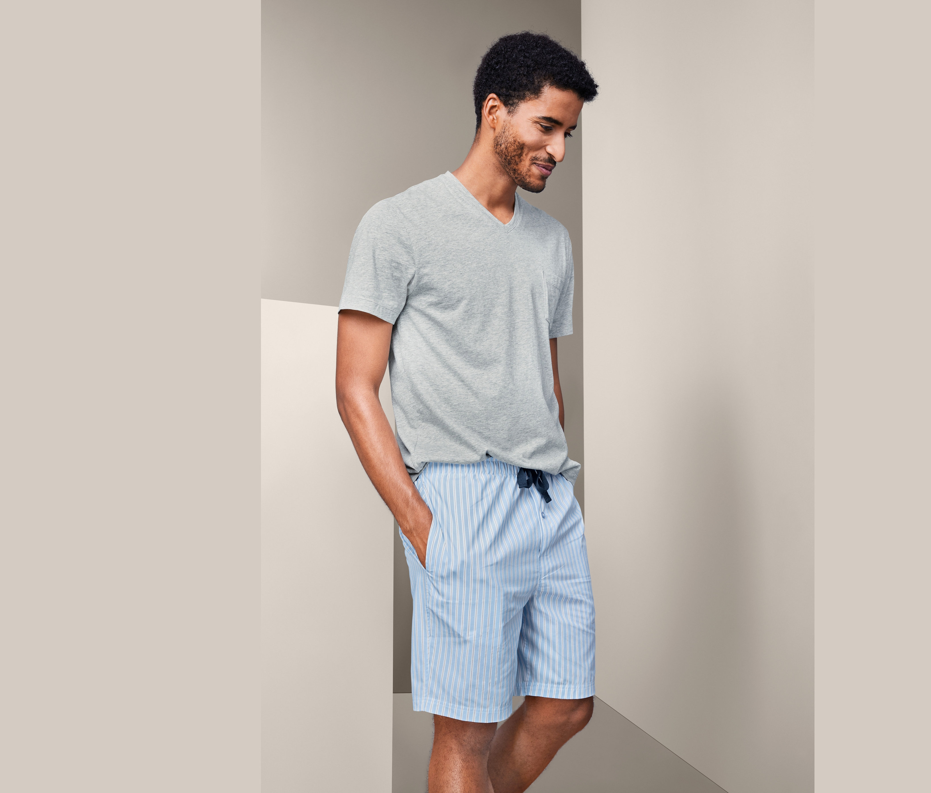 Mann trägt einen Shorty-Pyjama und ein graues T-Shirt.