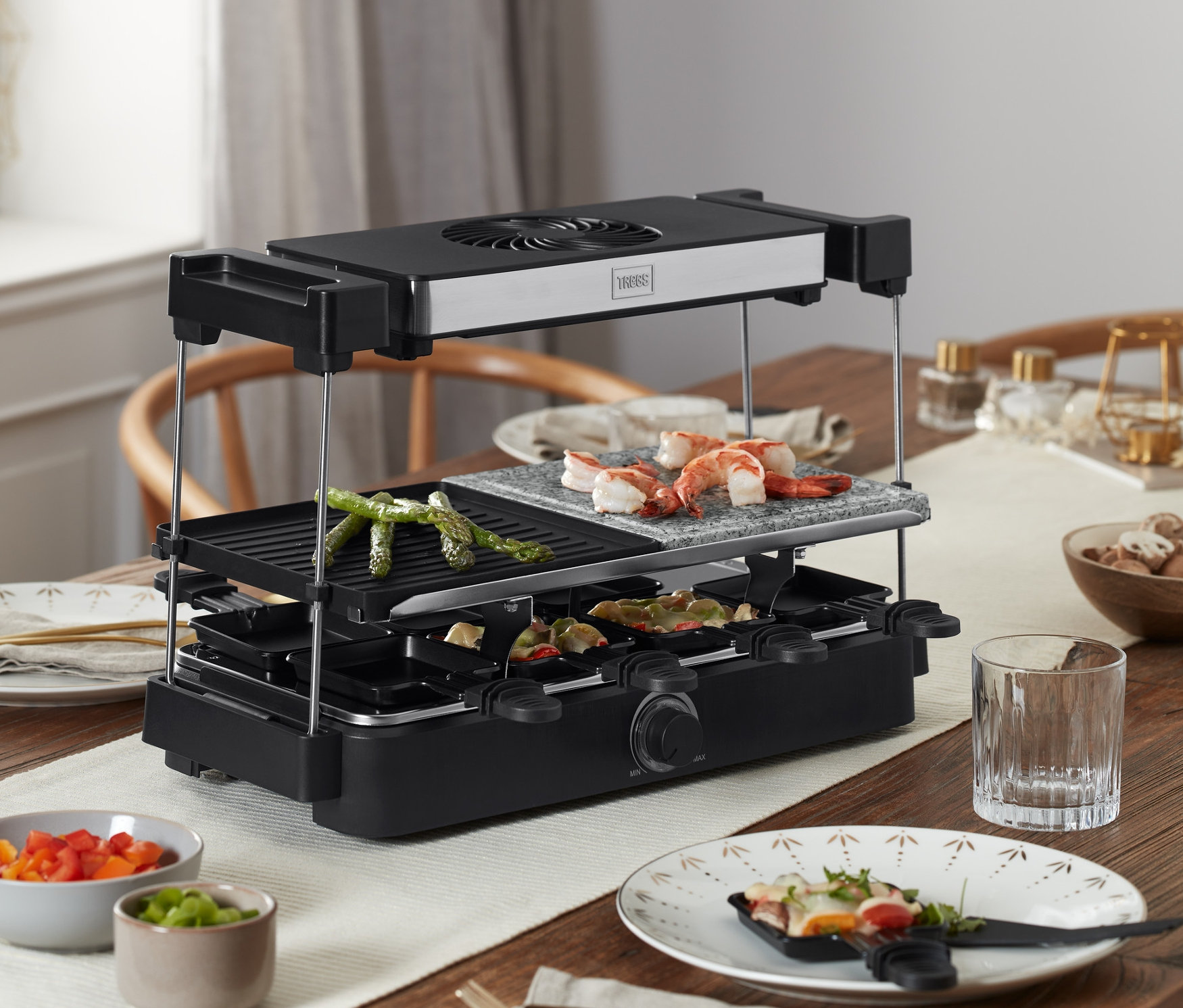 Auf einem Holztisch steht ein Trebs Raclette mit Dunstabzug und Steinplatte »15100«, auf dem Speisen gegrillt werden.