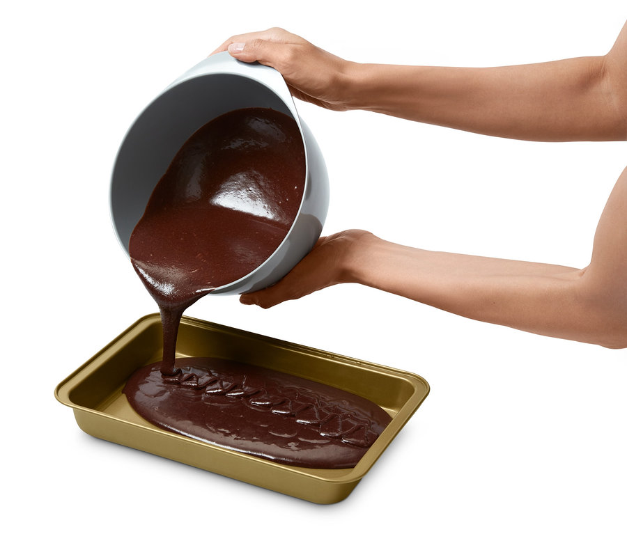 Brauner Teig wird aus einer Schüssel in eine Brownie-Backform gegossen.