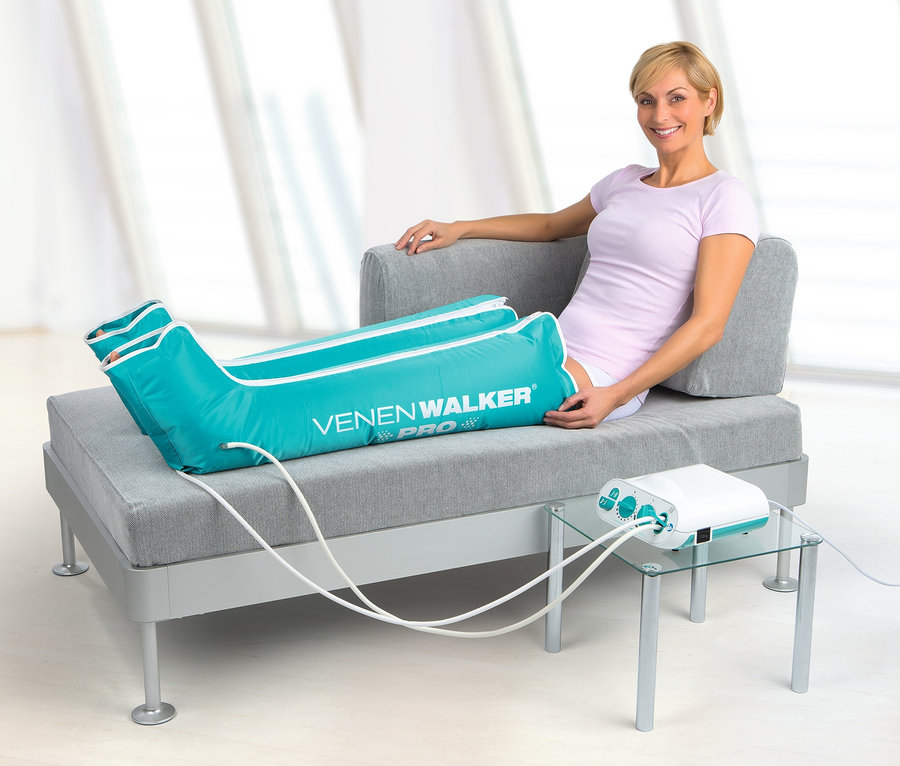 Frau sitzt auf der Couch und benutzt ein VenenWalker Pro2 Therapiegerät.