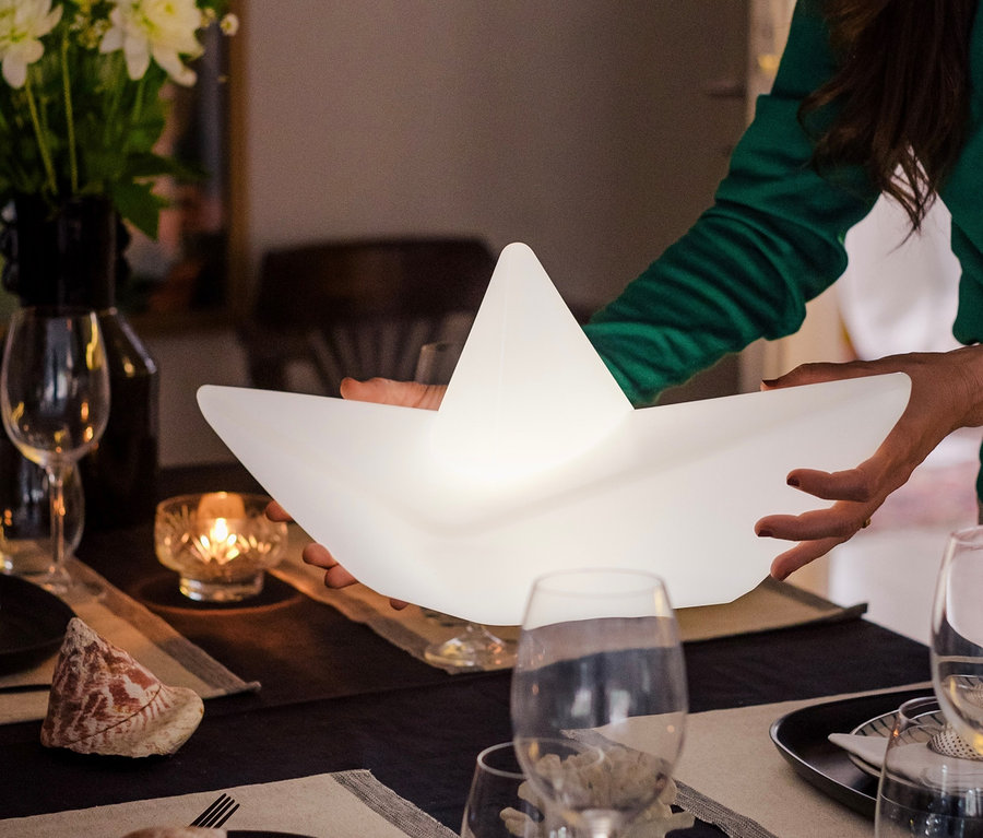 Frau hält Goodnight Light LED-Leuchte »Boot« über einen Tisch.