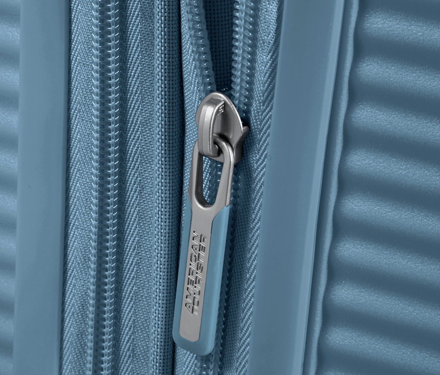 Detailaufnahme eines blauen American Tourister Soundbox Hartschalen-Koffers mit Reißverschluss.
