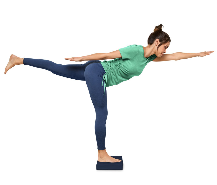 Frau macht Yoga-Pose auf Balance-Pad.