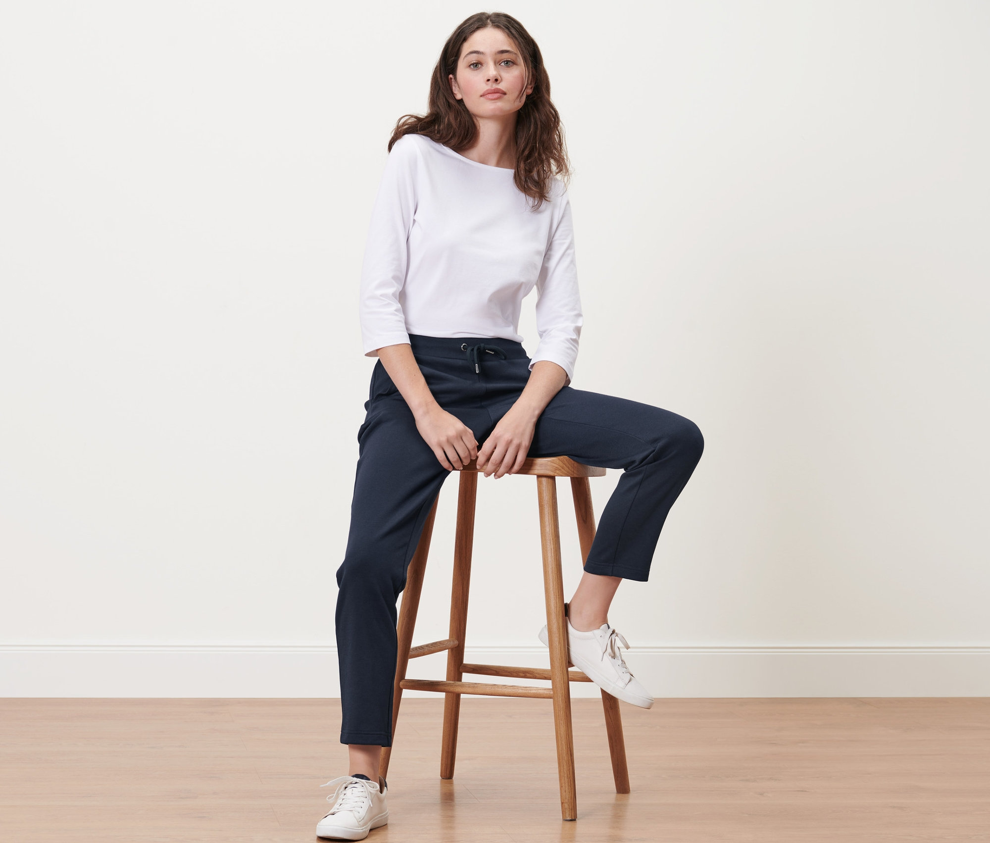 Frau sitzt auf einem Hocker und trägt eine dunkelblaue Joggpants.