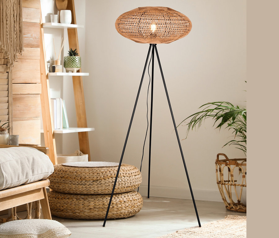 Im Raum steht eine Trio Stehleuchte »Hedda« mit einem braunen Rattanschirm auf einem schwarzen Stativ.