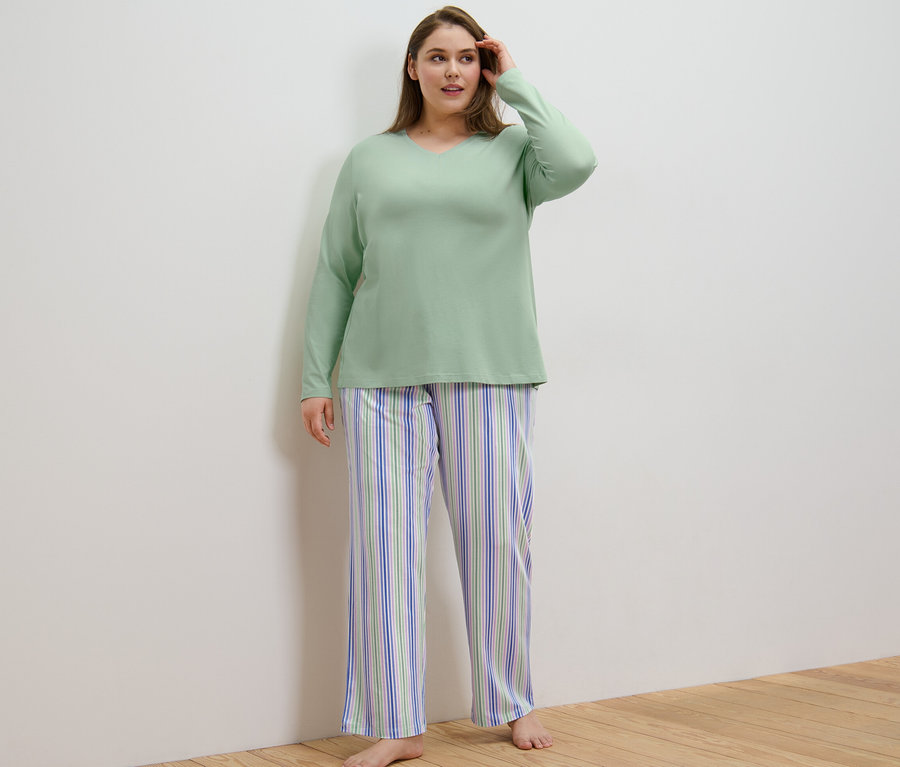 Frau trägt einen Pyjama und steht in einem Raum.