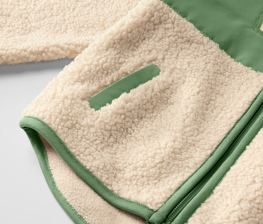 Detailansicht einer Kinder-Teddy-Jacke mit beigem Teddyplüsch und grünen Akzenten.