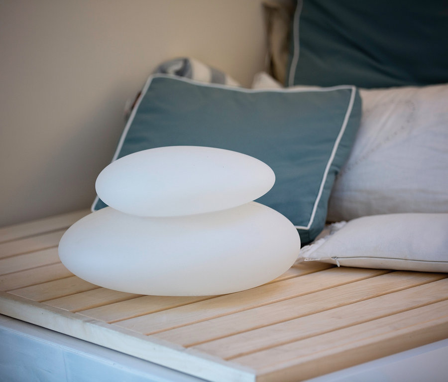 Zwei weiße 8 seasons design Solar-Leuchten, 39 cm, gestapelt auf einer Holzbank.