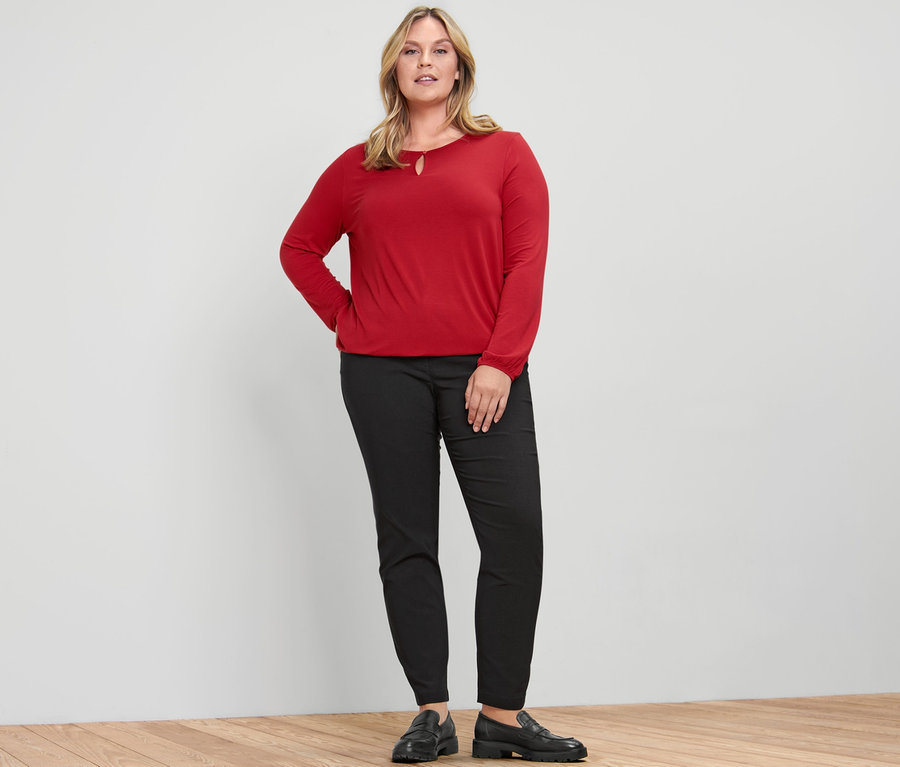 Frau posiert in rotem Blusenshirt.