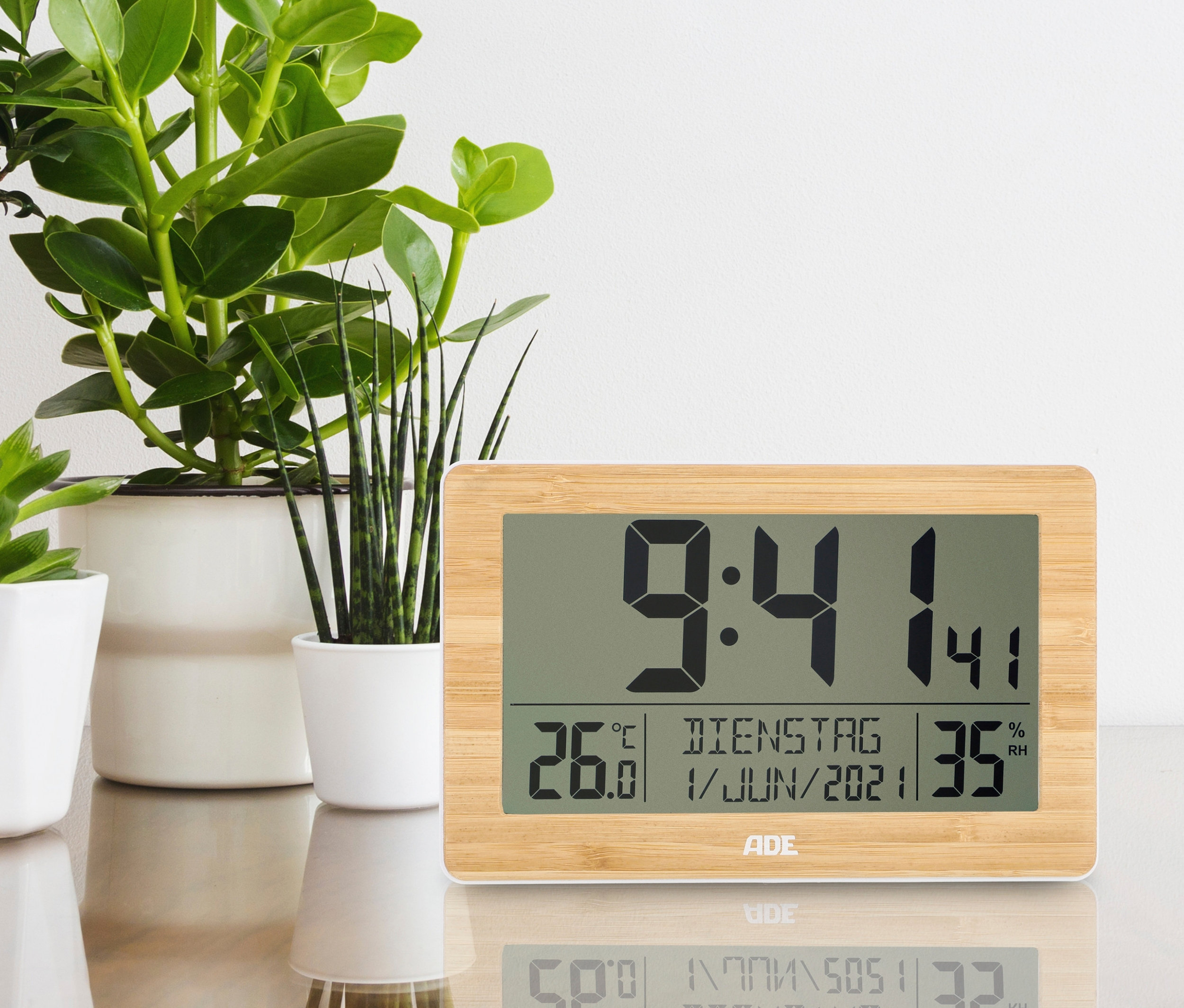 ADE DCF-Funkuhr mit XXL-Ziffern steht auf einem Tisch neben Pflanzen.