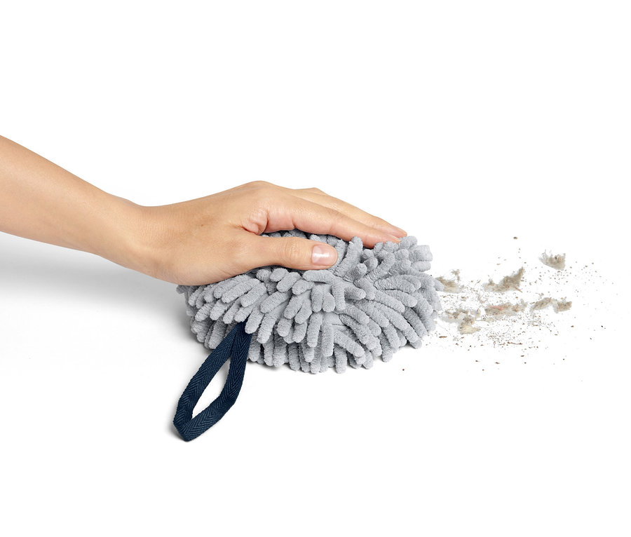 Hand drückt grauen Trockenball, um ihn herum Staub.