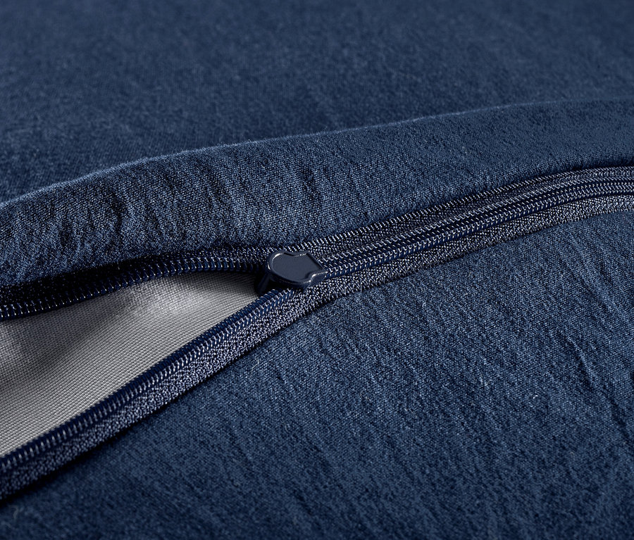 Detailaufnahme von marineblauer Bettwäsche mit Steppmuster und Reißverschluss.