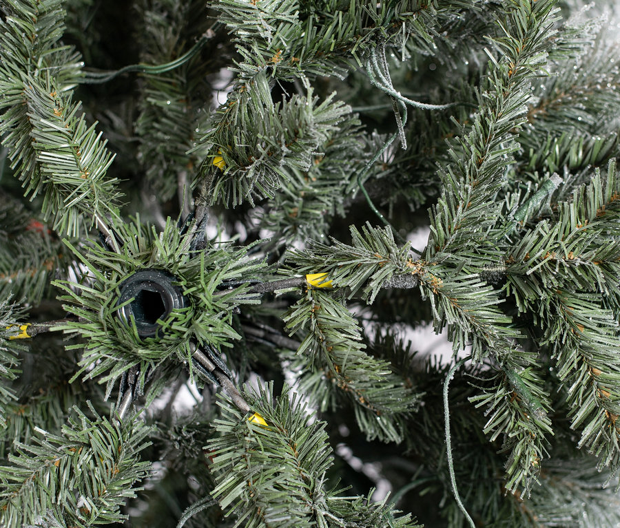 Detailansicht eines künstlichen, beschneiten Weihnachtsbaums "Fichte" mit LED-Lichterkette.
