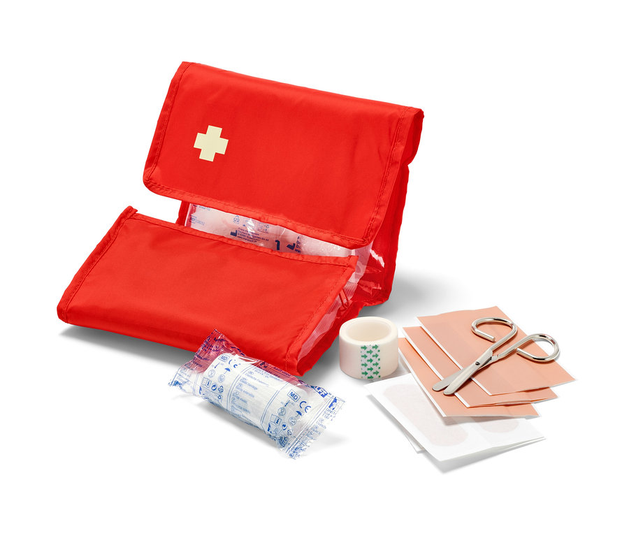 Geöffnete rote Erste-Hilfe-Fahrradtasche mit weißem Kreuz und Inhalt wie Verbände und Schere.