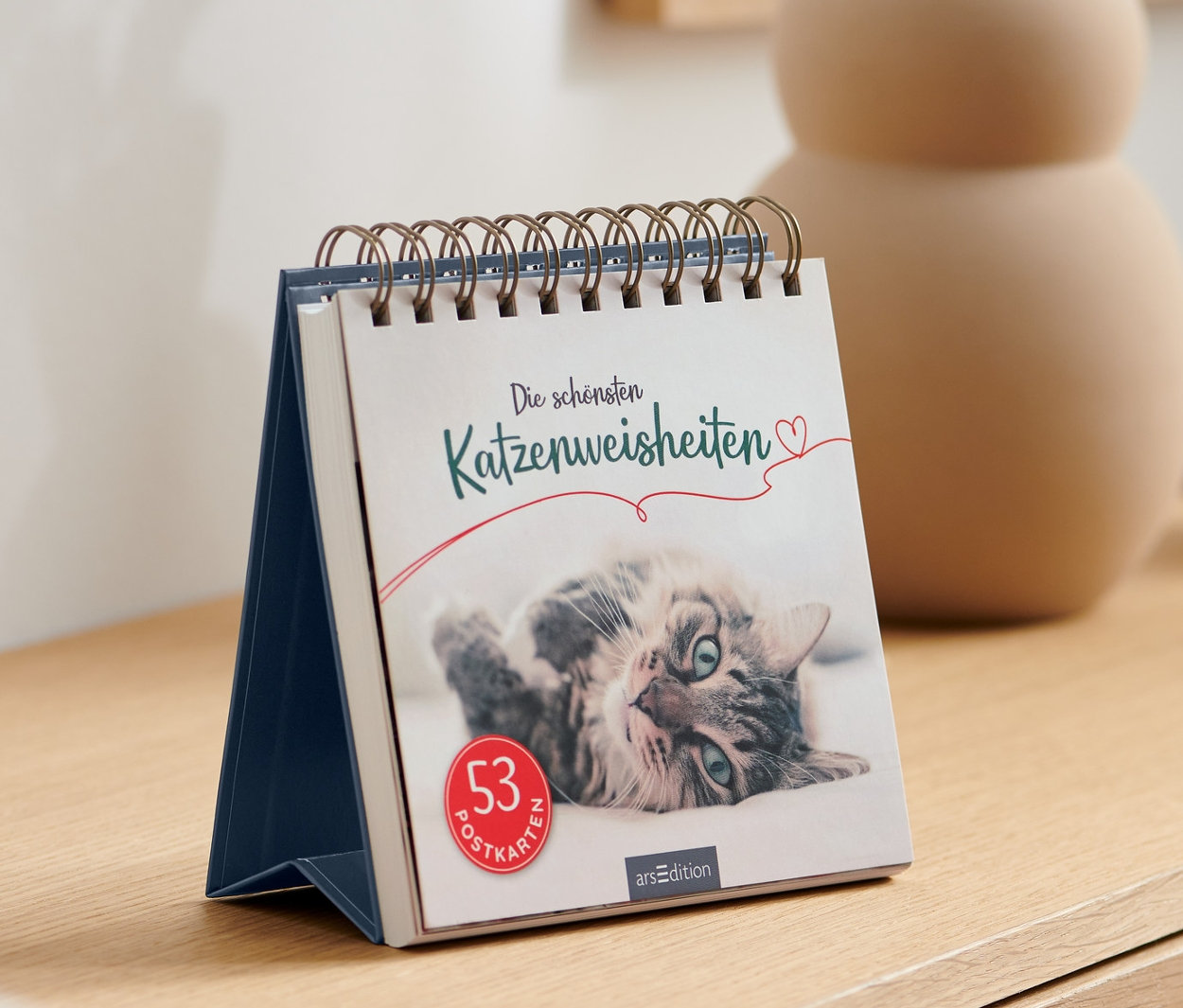 Auf einem Sideboard steht der Aufsteller »Die schönsten Katzenweisheiten«.