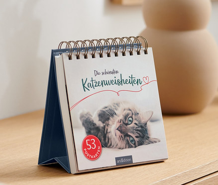 Auf einem Sideboard steht der Aufsteller »Die schönsten Katzenweisheiten«.