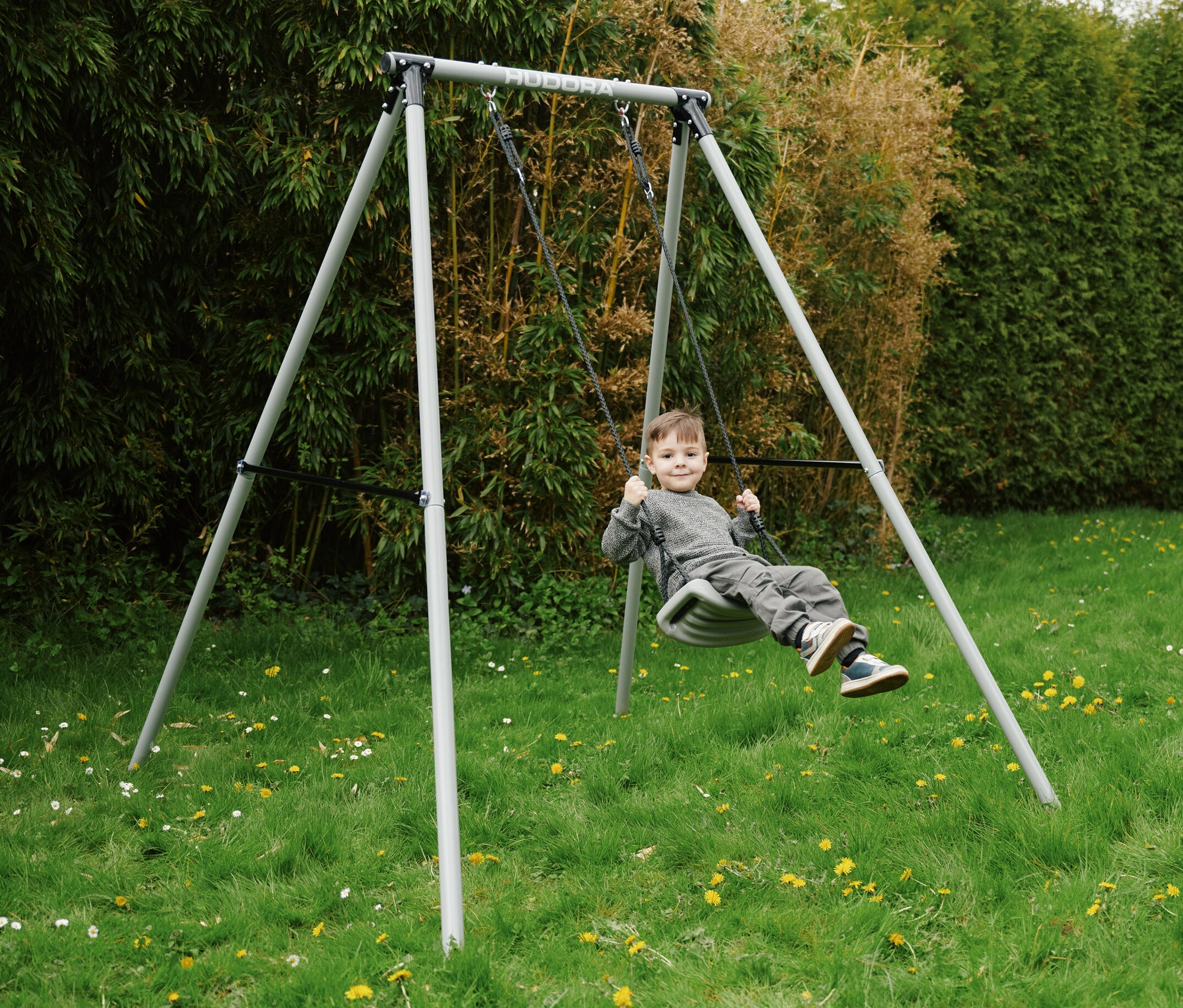 Ein Junge schaukelt auf einer grauen HUDORA Schaukel »Start« auf einer Wiese.
