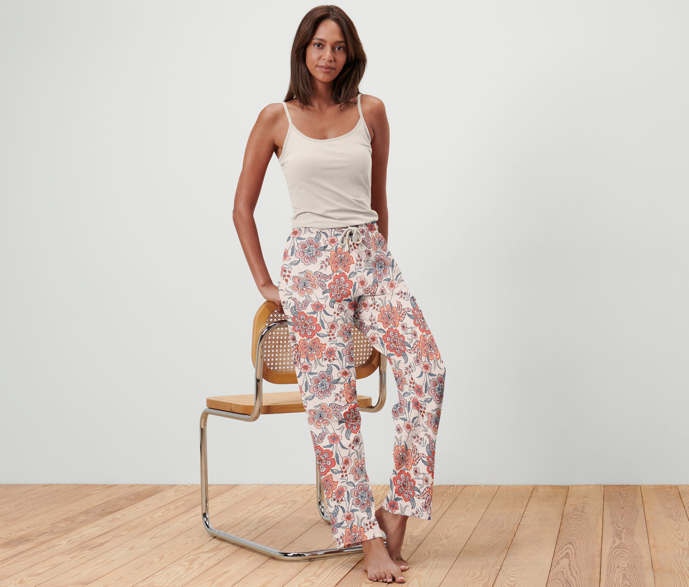 Frau posiert an einem Stuhl mit einer Pyjamahose.