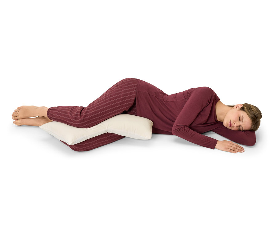 Frau liegt auf der Seite und umarmt ein Kissen.