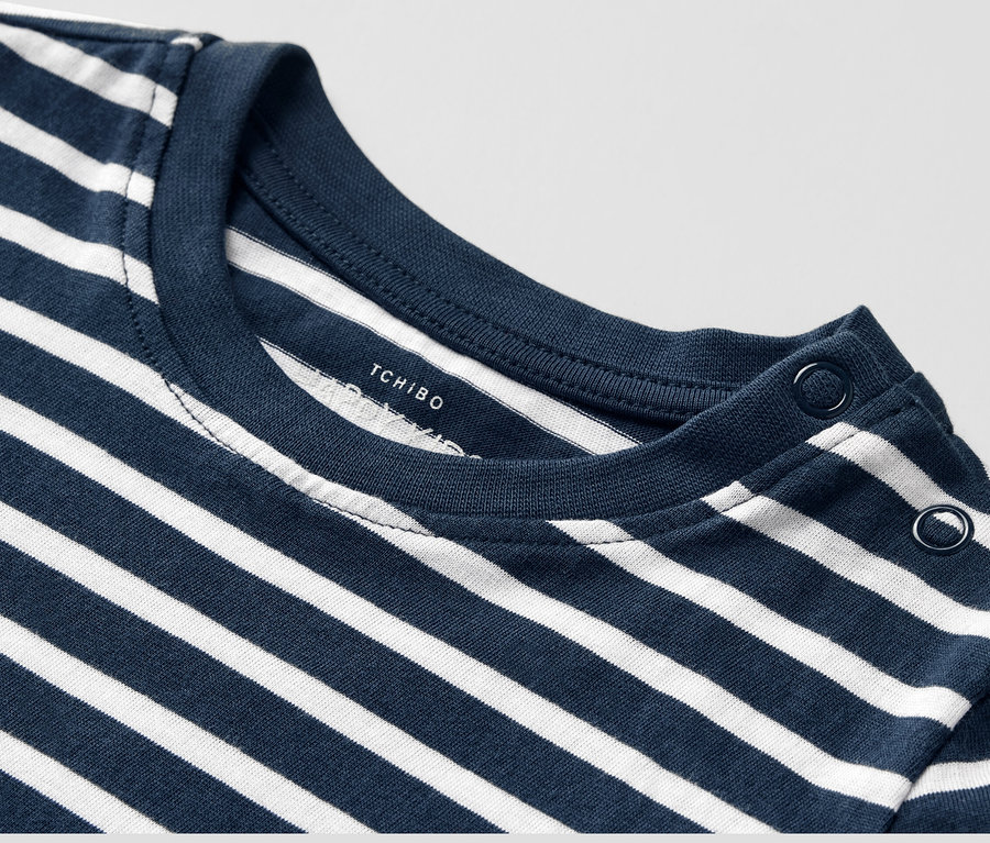 Detailansicht eines Kinder-Langarmshirts mit blau-weißen Streifen und Knöpfen an der Schulter.