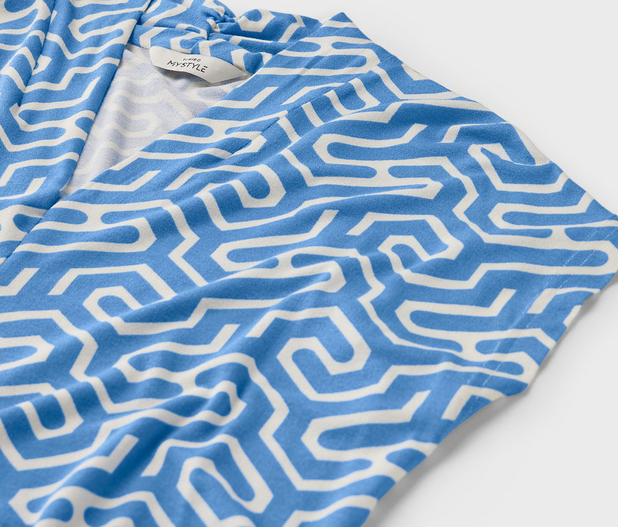 Detailansicht eines blauen Blusenshirts mit V-Ausschnitt und weißem geometrischen Muster.