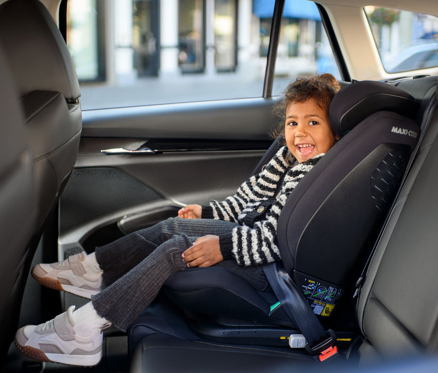 Ein Mädchen sitzt in einem schwarzen Maxi-Cosi Kinder-Autositz »Rodifix S«, i-Size im Auto und lacht.
