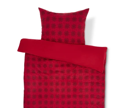Rote Bettwäsche mit dunkelrotem Schneeflockenmuster und Kopfkissen.