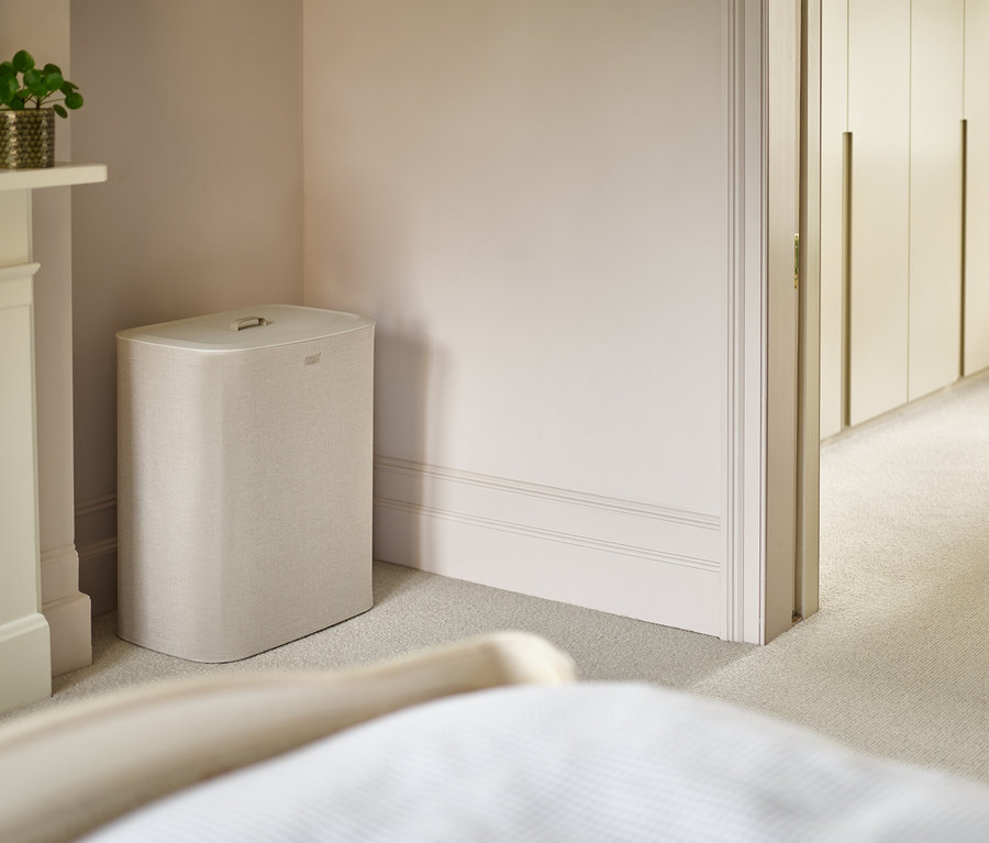 Ein beiger Wäschekorb steht in einer Ecke des Schlafzimmers neben einem Kamin.