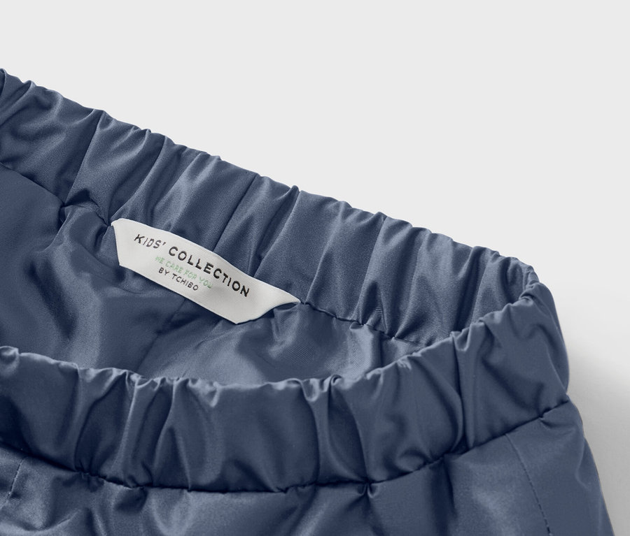 Detailaufnahme einer blauen Kinderhose mit Gummibund und einem Etikett mit der Aufschrift "Kids' Collection".