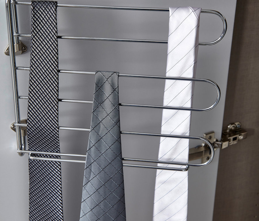 Drei Krawatten hängen an einem Krawattenhalter aus Metall.