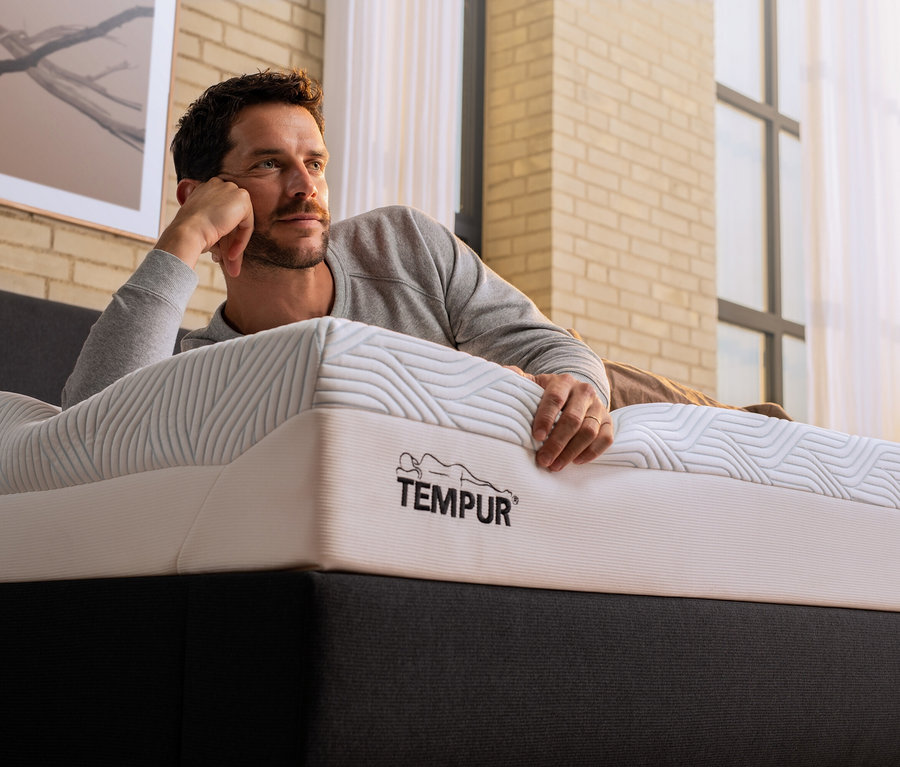 Mann liegt auf Tempur Matratze Prima, soft, und stützt sich auf seine Hand.