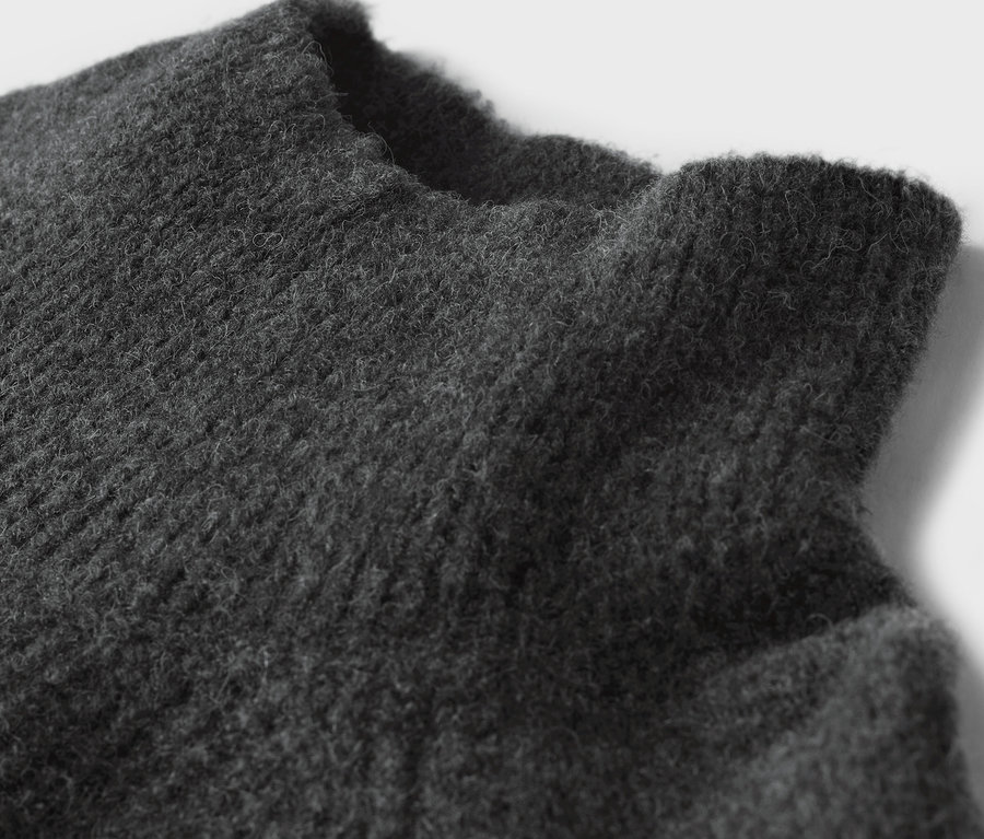 Detailaufnahme der Textur eines grauen Pullovers.