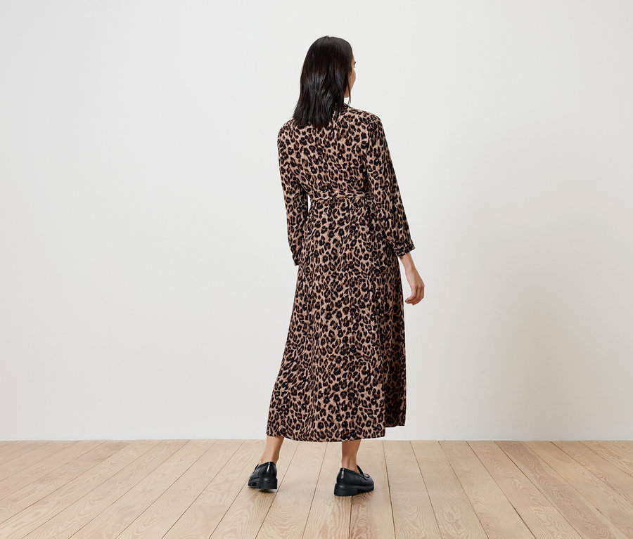 Frau mit langem Kleid im Tiermuster, den Rücken zur Kamera.